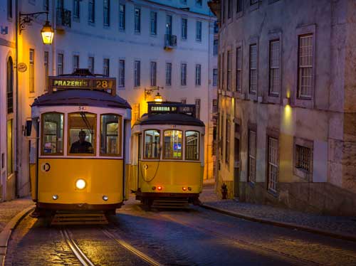 Travel Photo of two historic Tram 28 cars rounding an empty street corner in Lisbon, Portugal